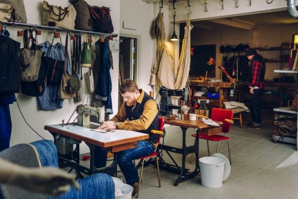 Trabalhador masculino usando máquina de costura na fábrica de sacos